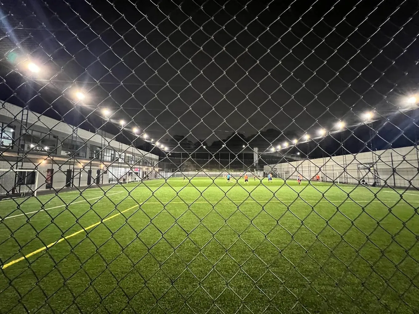 Campo de grama sintética da Arena Soccer Grass Alphaville à noite, com refletores acesos