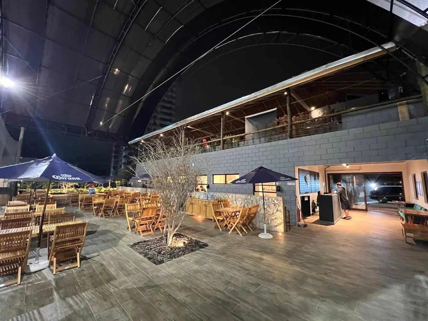 Deck do bar da arena, com mesas e ombrelones