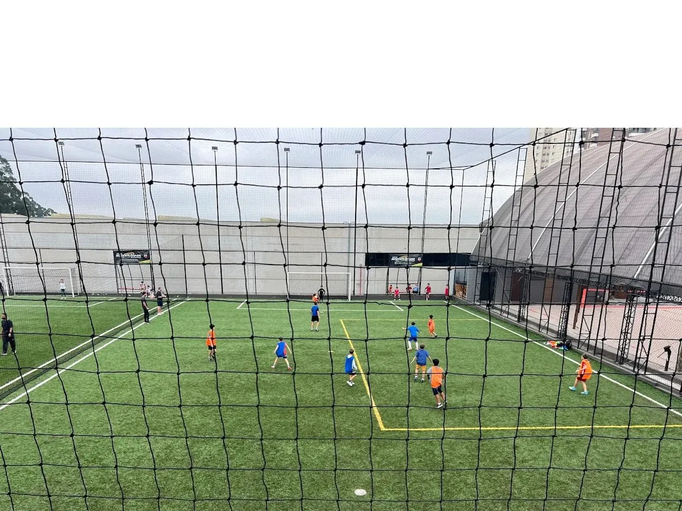 Jogo no campo visto por trás da rede do gol